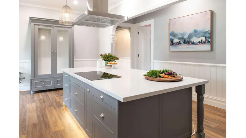 Stylish grey kitchen with island hob, white countertops, and stainless steel rangehood Stylish grey kitchen with island hob, white countertops, and stainless steel rangehood