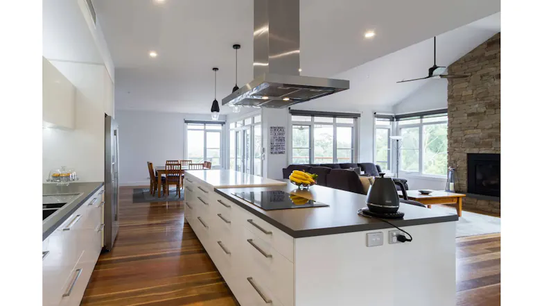 Spacious kitchen design with island rangehood, wood flooring, and adjoining living room Spacious kitchen design with island rangehood, wood flooring, and adjoining living room