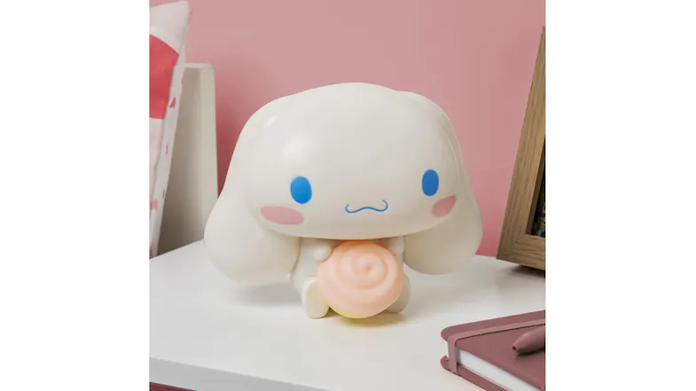 A white bunny-shaped night light (turned off), holding a swirl, is placed on a table with a notebook and a picture frame nearby A white bunny-shaped night light (turned off), holding a swirl, is placed on a table with a notebook and a picture frame nearby