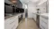 Modern kitchen with a built-in stainless steel rangehood, white cabinets, an island sink, and sleek lighting Modern kitchen with a built-in stainless steel rangehood, white cabinets, an island sink, and sleek lighting
