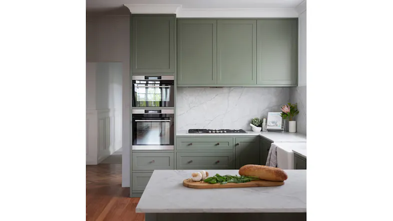 Modern kitchen with green cabinetry and marble surfaces, featuring a concealed undermount rangehood Modern kitchen with green cabinetry and marble surfaces, featuring a concealed undermount rangehood