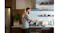 Person cooking at a stovetop beneath a stainless steel rangehood in a modern kitchen with shelves, dishes, and appliances Person cooking at a stovetop beneath a stainless steel rangehood in a modern kitchen with shelves, dishes, and appliances