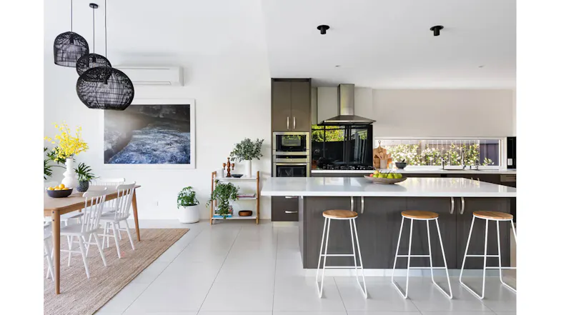 Open plan kitchen and dining space with island seating, pendant lights, stainless steel rangehood and bright natural lighting Open plan kitchen and dining space with island seating, pendant lights, stainless steel rangehood and bright natural lighting