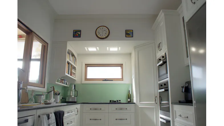Bright traditional kitchen with white cabinetry, green splashback and ceiling cassette rangehood modules installed above the cooktop area Bright traditional kitchen with white cabinetry, green splashback and ceiling cassette rangehood modules installed above the cooktop area