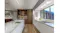 Modern kitchen with marble island, built-in sink, warm wood shelving, glassware display, large window, and sleek white cabinetry Modern kitchen with marble island, built-in sink, warm wood shelving, glassware display, large window, and sleek white cabinetry
