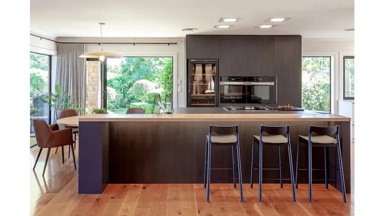 Warm kitchen with wooden island, bar seating and natural light flowing from the outdoor garden Warm kitchen with wooden island, bar seating and natural light flowing from the outdoor garden