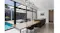 Spacious kitchen dining room with a wood table, black chairs and natural light from wall-to-wall windows Spacious kitchen dining room with a wood table, black chairs and natural light from wall-to-wall windows