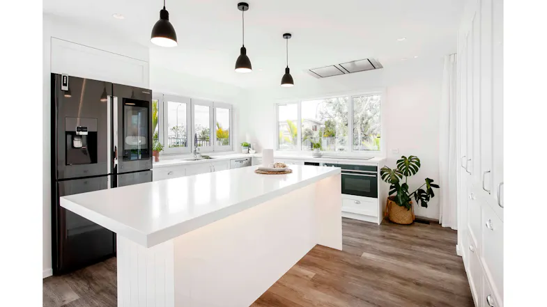 Bright white kitchen with an island, pendant lights, large windows, a stainless steel fridge, and an indoor plant Bright white kitchen with an island, pendant lights, large windows, a stainless steel fridge, and an indoor plant