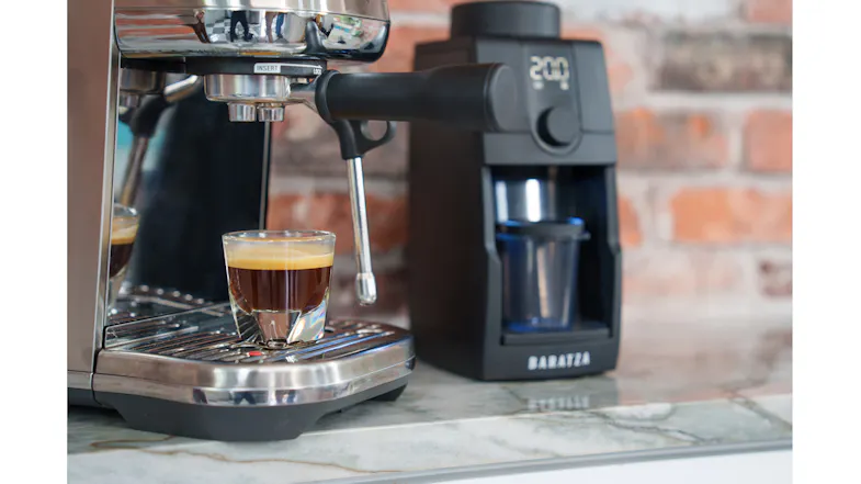 An espresso machine alongside the grinder, featuring a fresh shot An espresso machine alongside the grinder, featuring a fresh shot