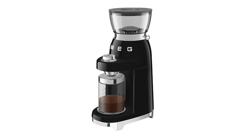 Angled view of the grinder with freshly ground coffee collected in the transparent container, demonstrating its use Angled view of the grinder with freshly ground coffee collected in the transparent container, demonstrating its use