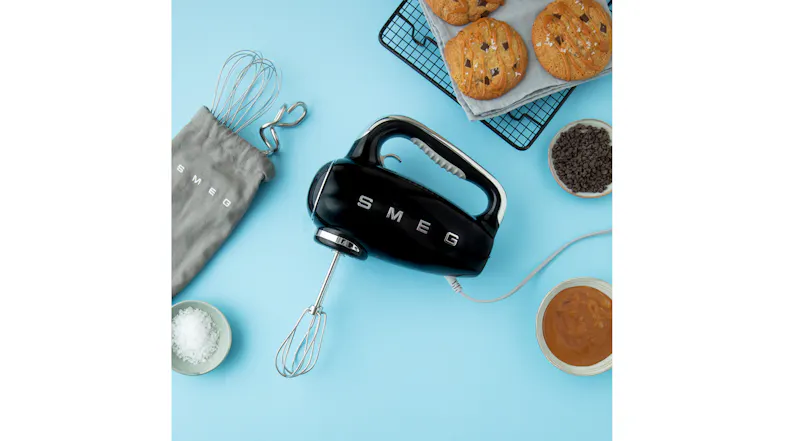 A kitchen counter showing cookies and a hand mixer A kitchen counter showing cookies and a hand mixer