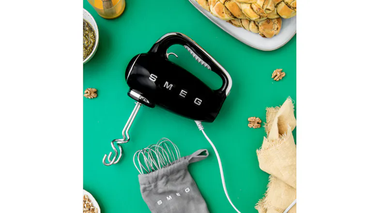 Top-down view of a green surface featuring a Smeg mixer with a dough hook Top-down view of a green surface featuring a Smeg mixer with a dough hook