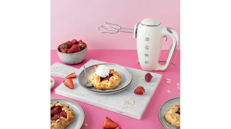 Pink counter with a Smeg hand mixer, highlighting fresh strawberry tarts Pink counter with a Smeg hand mixer, highlighting fresh strawberry tarts