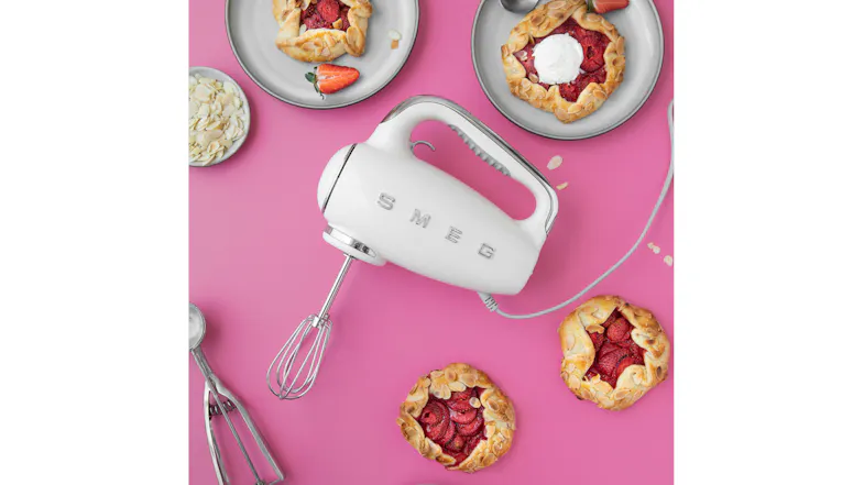 Pink counter with a Smeg hand mixer, highlighting fresh strawberry tarts Pink counter with a Smeg hand mixer, highlighting fresh strawberry tarts