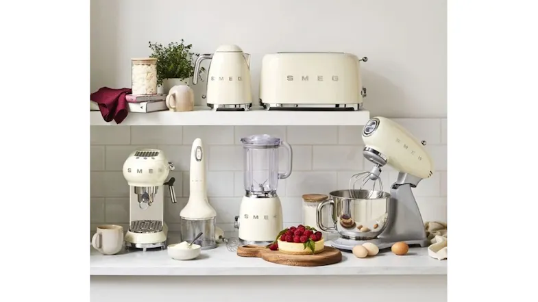 Kitchen countertop display featuring multiple cream Smeg appliances, including a stand mixer Kitchen countertop display featuring multiple cream Smeg appliances, including a stand mixer