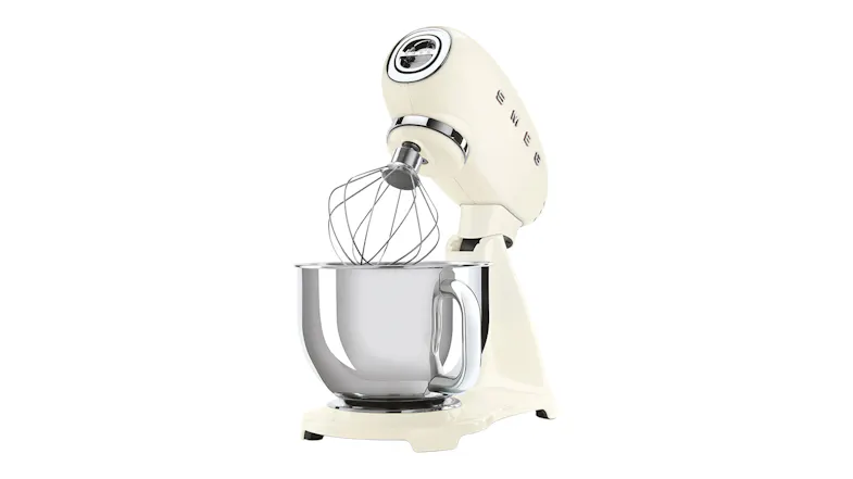 Cream Smeg 50’s Style stand mixer with tilt head raised and wire whisk attachment above a mixing bowl Cream Smeg 50’s Style stand mixer with tilt head raised and wire whisk attachment above a mixing bowl