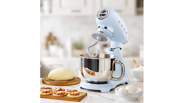 Pastel blue Smeg 50’s Style stand mixer with tilt head raised and dough hook over a stainless steel mixing bowl Pastel blue Smeg 50’s Style stand mixer with tilt head raised and dough hook over a stainless steel mixing bowl
