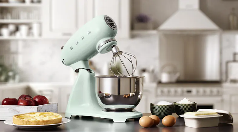Stand mixer with tilt head raised and wire whisk over a stainless steel bowl on a kitchen counter Stand mixer with tilt head raised and wire whisk over a stainless steel bowl on a kitchen counter
