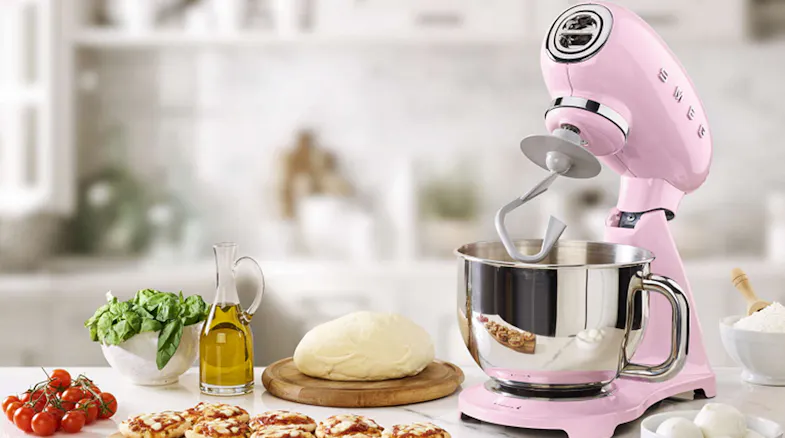 Stand mixer with tilt head raised and dough hook inside a stainless steel bowl on a kitchen countertop Stand mixer with tilt head raised and dough hook inside a stainless steel bowl on a kitchen countertop