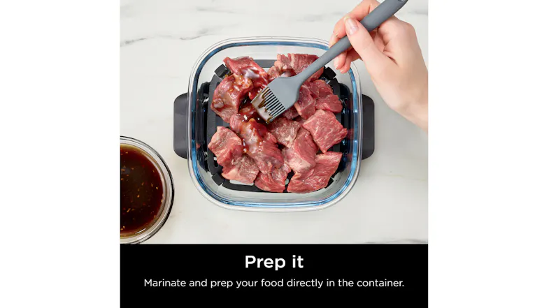Close-up view of a person marinating food, showcasing the Ninja container with raw meat Close-up view of a person marinating food, showcasing the Ninja container with raw meat