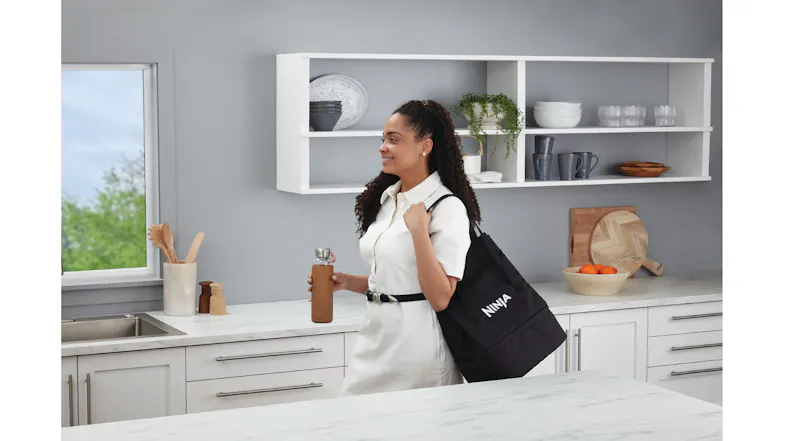 A woman in a white dress carrying a black tote bag on her shoulder A woman in a white dress carrying a black tote bag on her shoulder