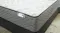 Close-up of a Sleepmaker Serene Extra Firm mattress corner, showing a white quilted top pattern and a grey, wavy-textured side panel Close-up of a Sleepmaker Serene Extra Firm mattress corner, showing a white quilted top pattern and a grey, wavy-textured side panel
