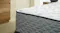 Close-up of a Serene mattress corner with a white quilted top surface and a dark grey, wave-patterned textured side fabric Close-up of a Serene mattress corner with a white quilted top surface and a dark grey, wave-patterned textured side fabric