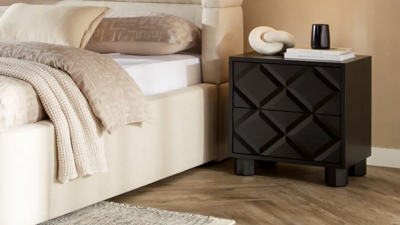 Stylish bedroom setup with black bedside cabinet, neutral bedding, and warm-toned wall backdrop Stylish bedroom setup with black bedside cabinet, neutral bedding, and warm-toned wall backdrop
