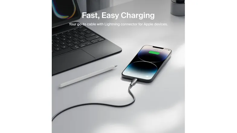 Belkin Lightning cable charging iPhone beside laptop and stylus on desk, phone screen shows 100 per cent battery Belkin Lightning cable charging iPhone beside laptop and stylus on desk, phone screen shows 100 per cent battery