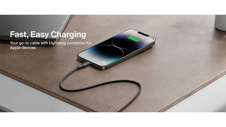 An iPhone is charging on a brown leather desk mat with a black braided Belkin Lightning cable An iPhone is charging on a brown leather desk mat with a black braided Belkin Lightning cable