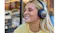 Close-up of a smiling blonde woman wearing black JBL over-ear headphones and a yellow sweater Close-up of a smiling blonde woman wearing black JBL over-ear headphones and a yellow sweater