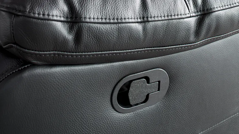 Close-up of the black manual recline latch set into the leather side of a Nomad sofa Close-up of the black manual recline latch set into the leather side of a Nomad sofa