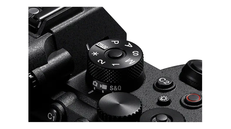 A detailed close-up angle focusing on the camera's top textured main exposure mode control dial A detailed close-up angle focusing on the camera's top textured main exposure mode control dial