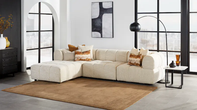 Adelaide fabric modular sofa with attached left-facing chaise chaise on a brown rug Adelaide fabric modular sofa with attached left-facing chaise chaise on a brown rug