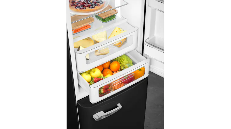 Fridge drawers filled with fruit, vegetables, and cheese, with a berry tart on the shelf above Fridge drawers filled with fruit, vegetables, and cheese, with a berry tart on the shelf above