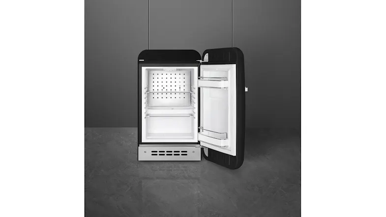 A retro black bar fridge open in a modern room, displaying empty shelves and door storage compartments A retro black bar fridge open in a modern room, displaying empty shelves and door storage compartments