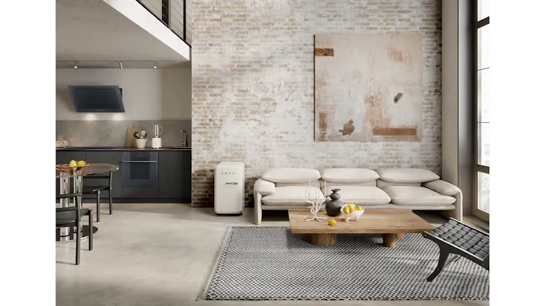 Modern open-plan kitchen and living room with brick wall, beige sofa, wood coffee table, and Smeg mini fridge Modern open-plan kitchen and living room with brick wall, beige sofa, wood coffee table, and Smeg mini fridge