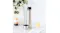 Stainless steel vacuum flask with cup lid beside a glass mug of tea on a marble countertop with plant decor Stainless steel vacuum flask with cup lid beside a glass mug of tea on a marble countertop with plant decor