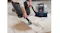 A person vacuuming a large brown stain on a geometric rug A person vacuuming a large brown stain on a geometric rug