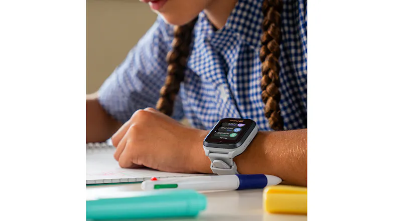 A child writing on paper, highlighting the grey smartwatch A child writing on paper, highlighting the grey smartwatch