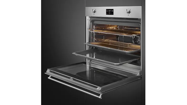 Angled view of an open stainless steel Smeg oven, displaying racks and a tray with an illuminated interior Angled view of an open stainless steel Smeg oven, displaying racks and a tray with an illuminated interior