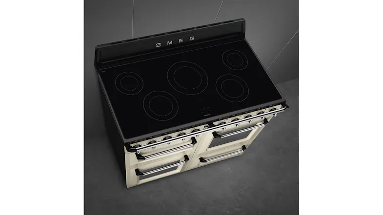 An angled top-down view of a five-zone black glass induction cooktop of a Smeg freestanding range cooker An angled top-down view of a five-zone black glass induction cooktop of a Smeg freestanding range cooker