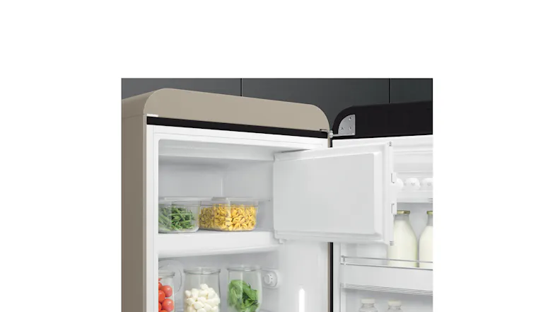 Compact fridge interior with a small freezer open, showing containers of vegetables, pasta, and jars Compact fridge interior with a small freezer open, showing containers of vegetables, pasta, and jars