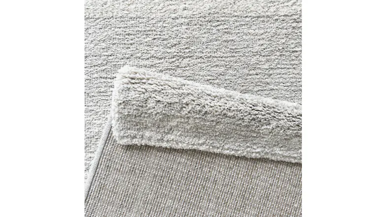 Underside of rug showing backing material and edge stitching in neutral grey finish Underside of rug showing backing material and edge stitching in neutral grey finish
