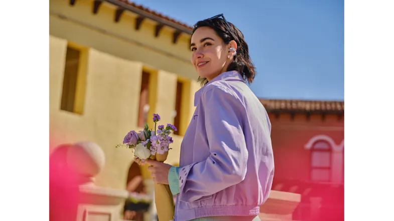 Side view of a person holding flowers with Shokz open-ear earbuds Side view of a person holding flowers with Shokz open-ear earbuds