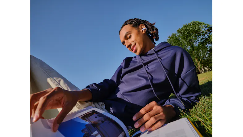 High-angle view of a person reading a book while wearing earbuds outdoors High-angle view of a person reading a book while wearing earbuds outdoors