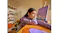 Side view of a woman looking at a desktop monitor with purple earbuds Side view of a woman looking at a desktop monitor with purple earbuds
