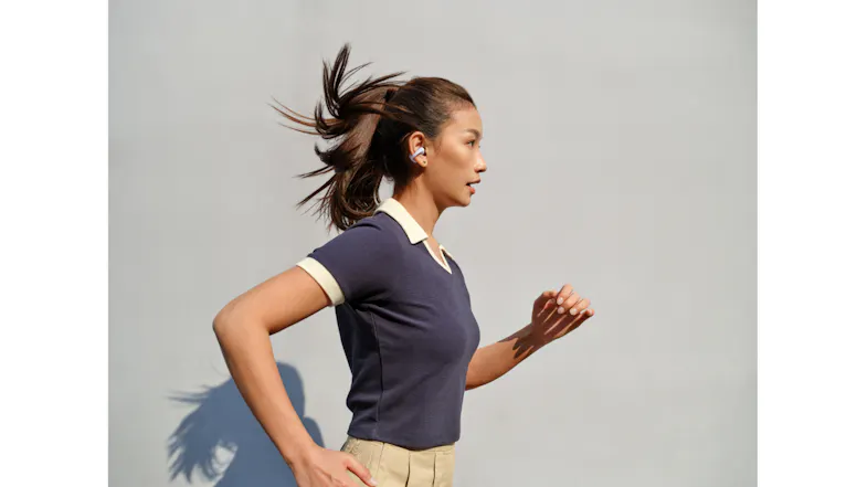 Profile view of a person wearing an earbud while running against a plain wall Profile view of a person wearing an earbud while running against a plain wall