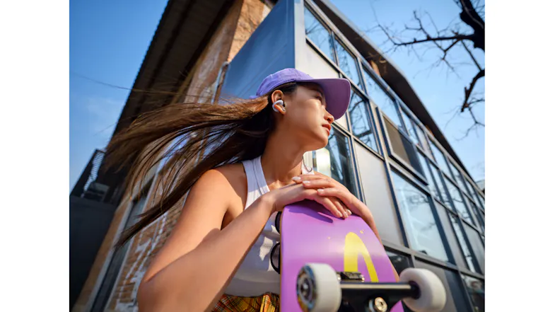 Low-angle view of a person holding a purple skateboard with matching earbuds Low-angle view of a person holding a purple skateboard with matching earbuds