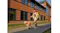 Distant view of a person walking a dog past buildings while wearing earbuds Distant view of a person walking a dog past buildings while wearing earbuds